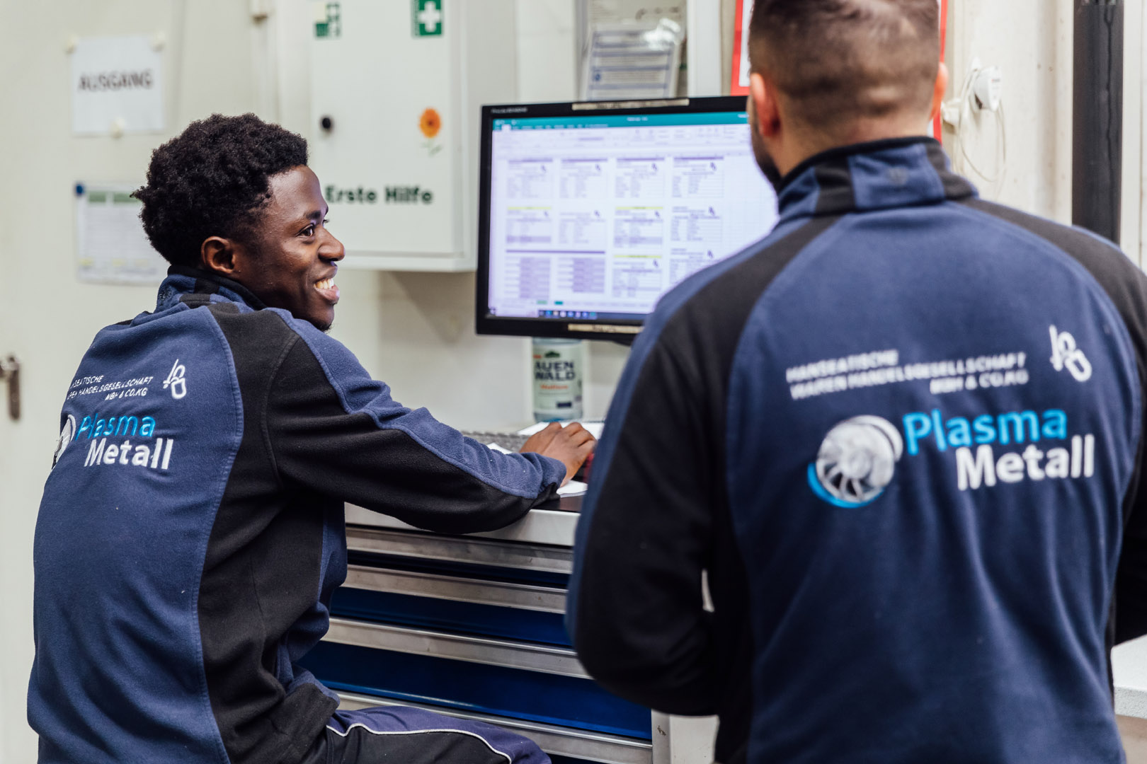 Two colleagues enter data on the computer and smile.