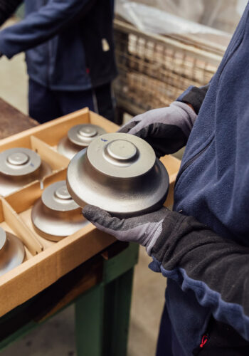 An employee holds a raw product for a turbocharger wheel in his hand.